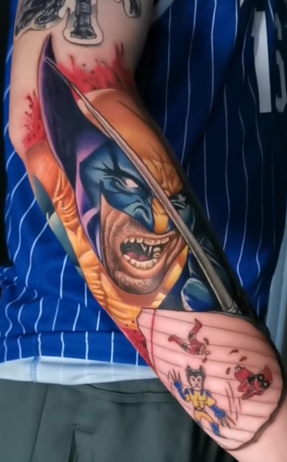 Tattoo of a superhero on a person's arm with a blue plaid shirt. Wolverine